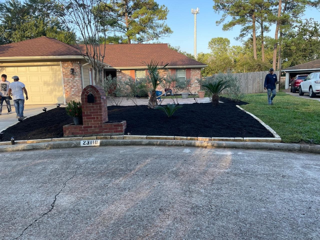 The same front yard bed finished with stone edging and fresh dark mulch around established plantings